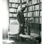 Bruno Kalniņš (1899-1990) przy półce z książkami w swoim mieszkaniu. Sztokholm pod koniec lat pięćdziesiątych XX w. Zdj. Fotograf nieznany / Łotewskie Narodowe Muzeum Historyczne.